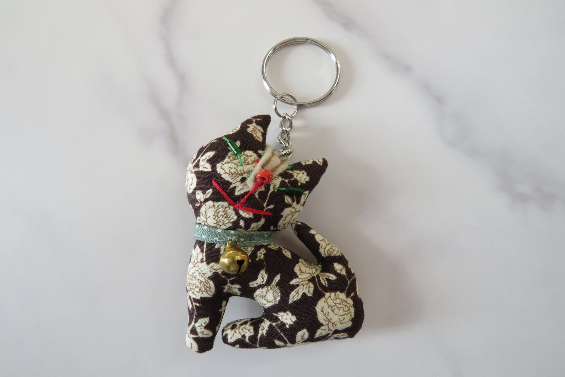 Floral-patterned fabric cat keyring.