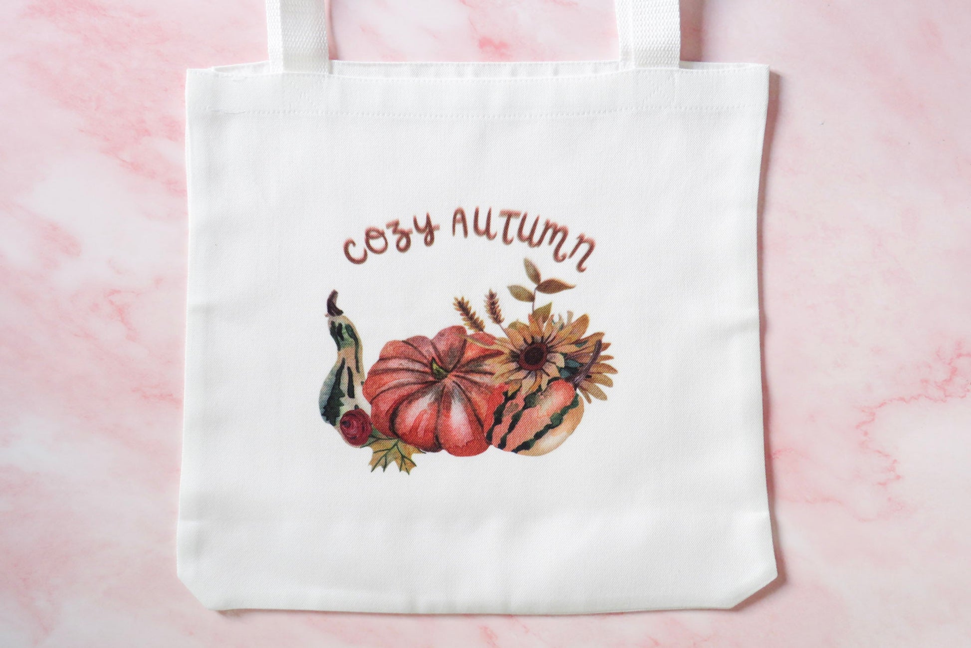 White tote bag with 'Cozy Autumn' text and pumpkin design.
