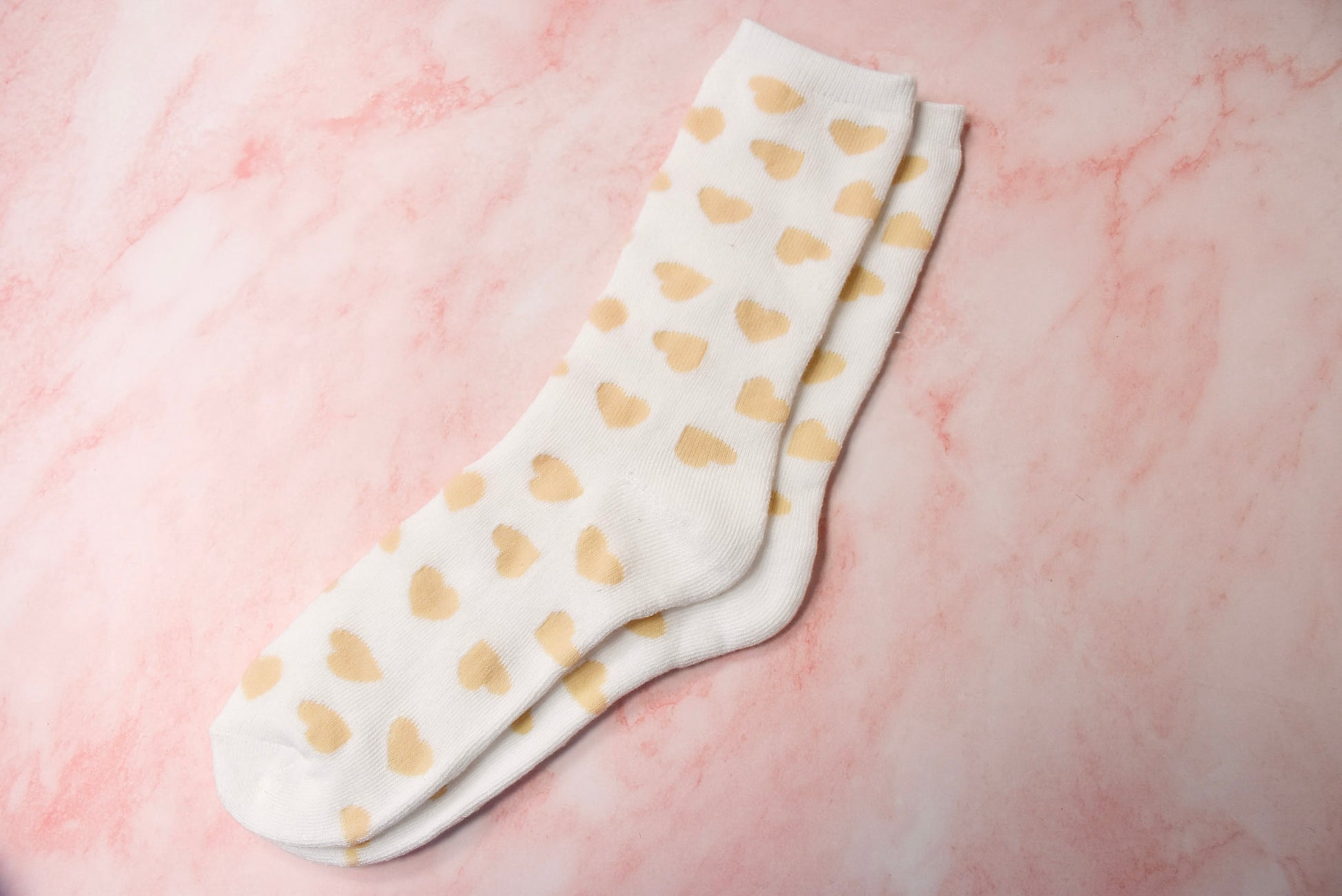 A pair of white socks with a gold heart pattern.