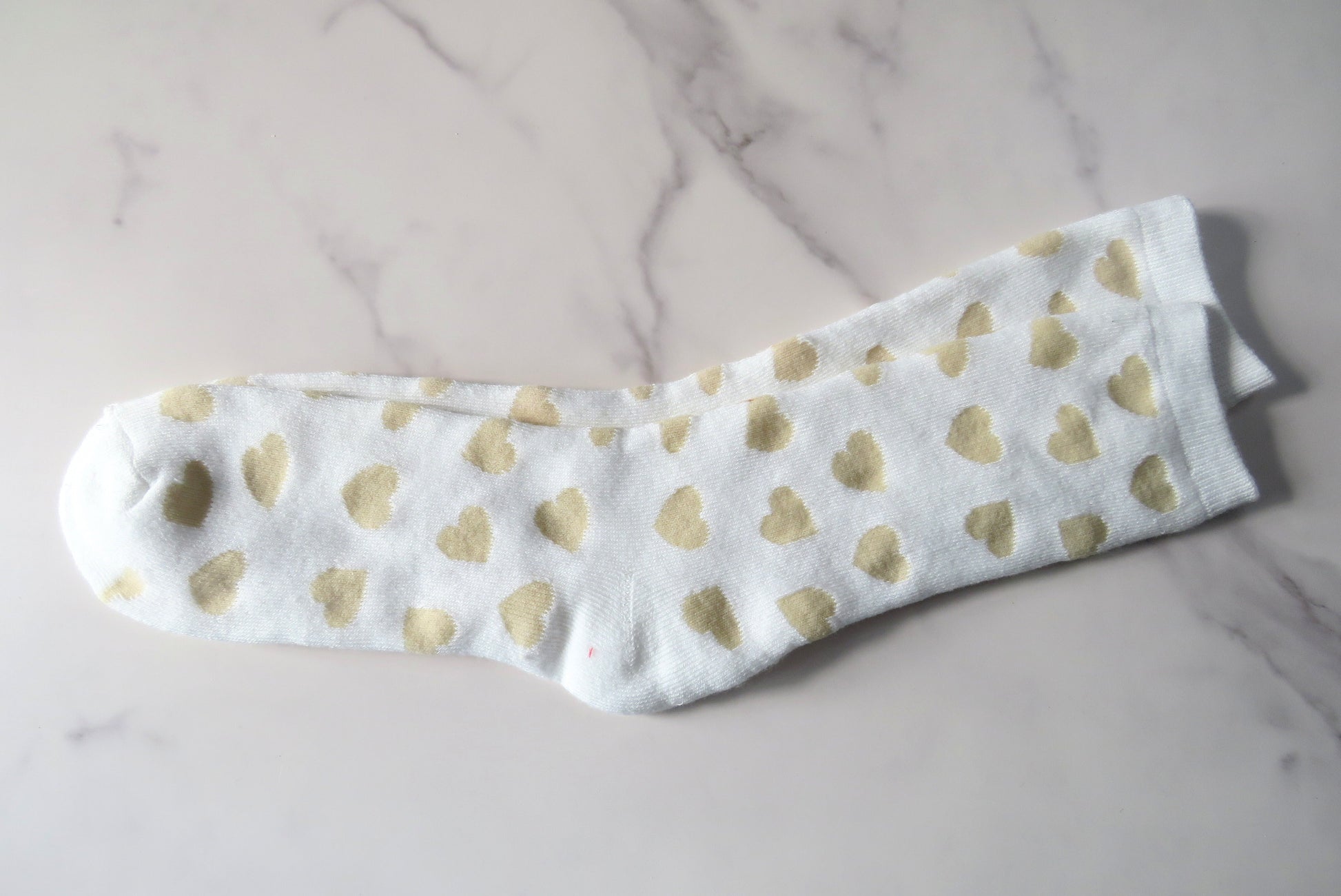 A pair of white socks with a gold heart pattern.