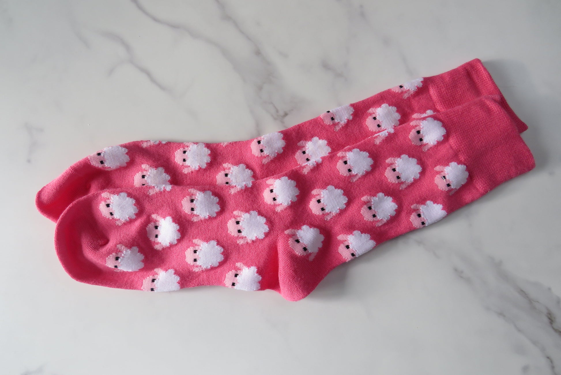 Pink sock with white sheep pattern on.