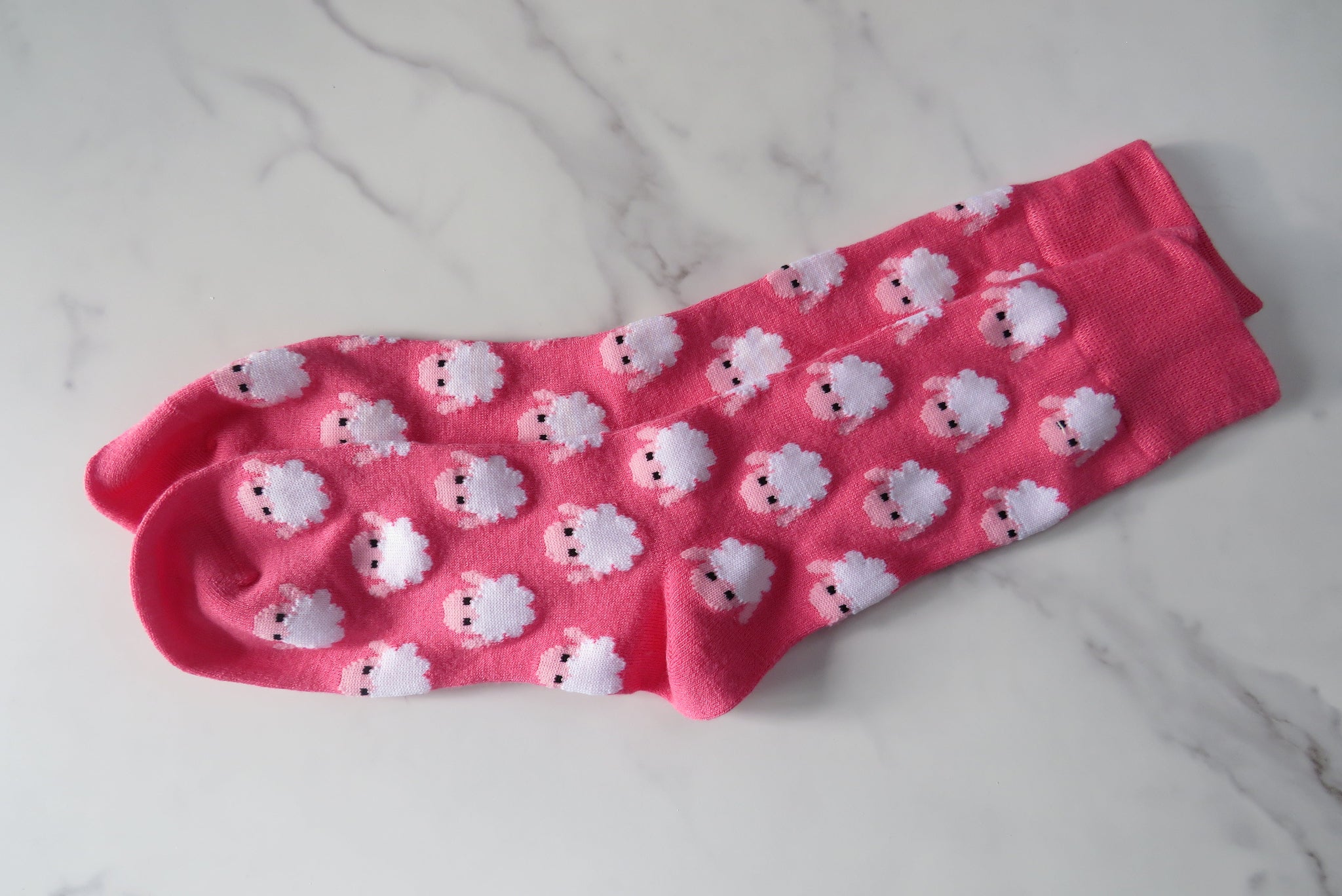 Pink sock with white sheep pattern on.