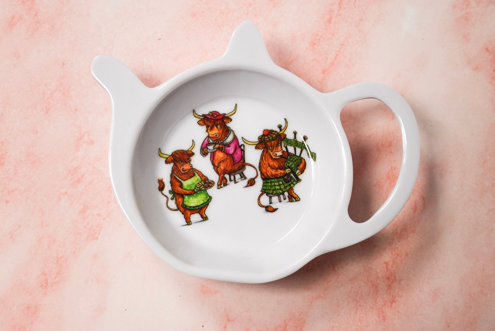 A white ceramic tea tray with a handle, featuring a whimsical illustration of three cows in colourful costumes playing musical instruments.