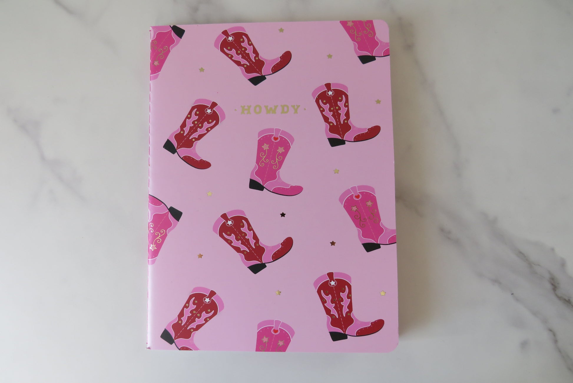 Notebook with pink cowboy boot pattern and 'Howdy' text on a pink background.