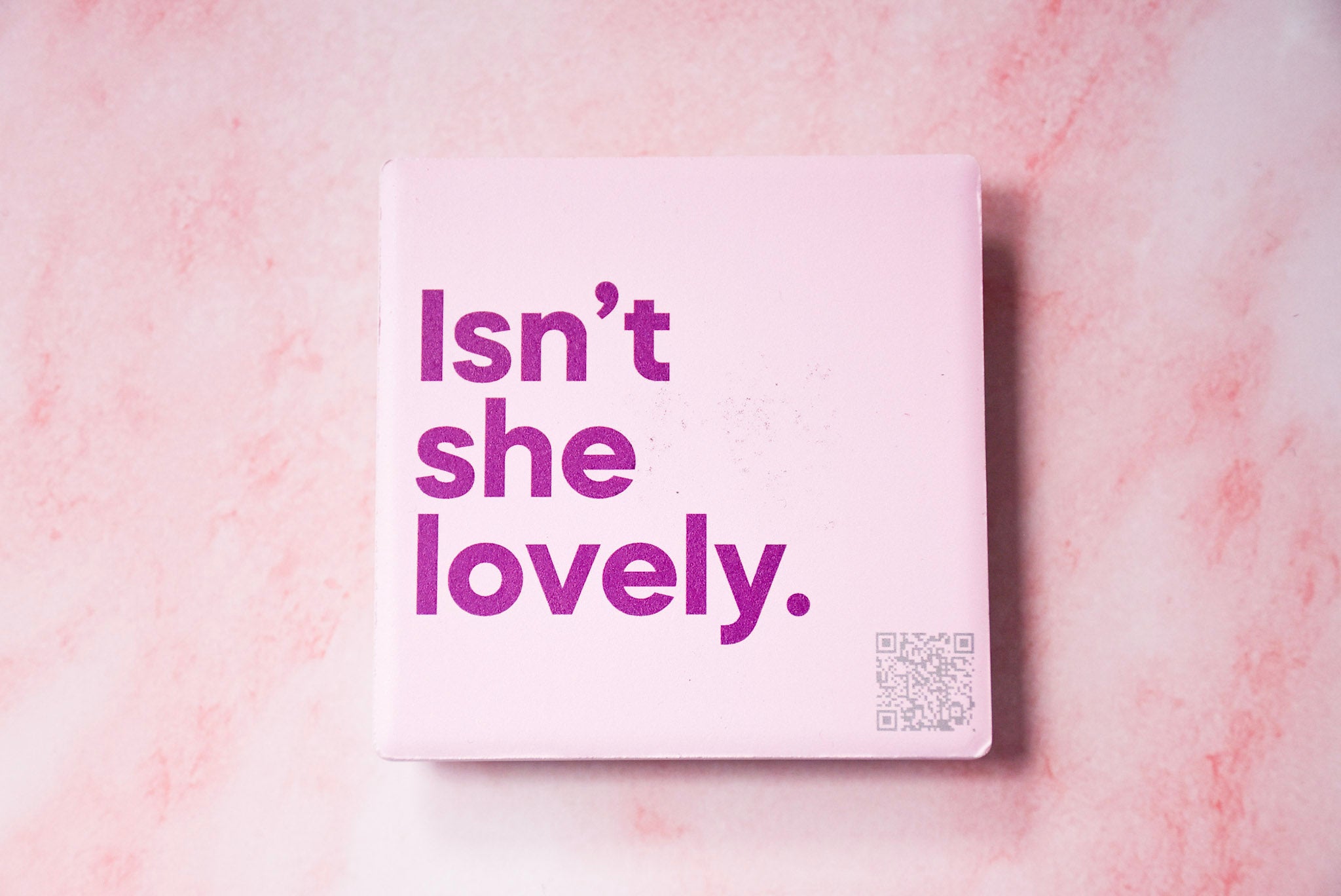 A square pink magnet with the text 'Isn't she lovely.' on it, scan the QR code and it will play the song.