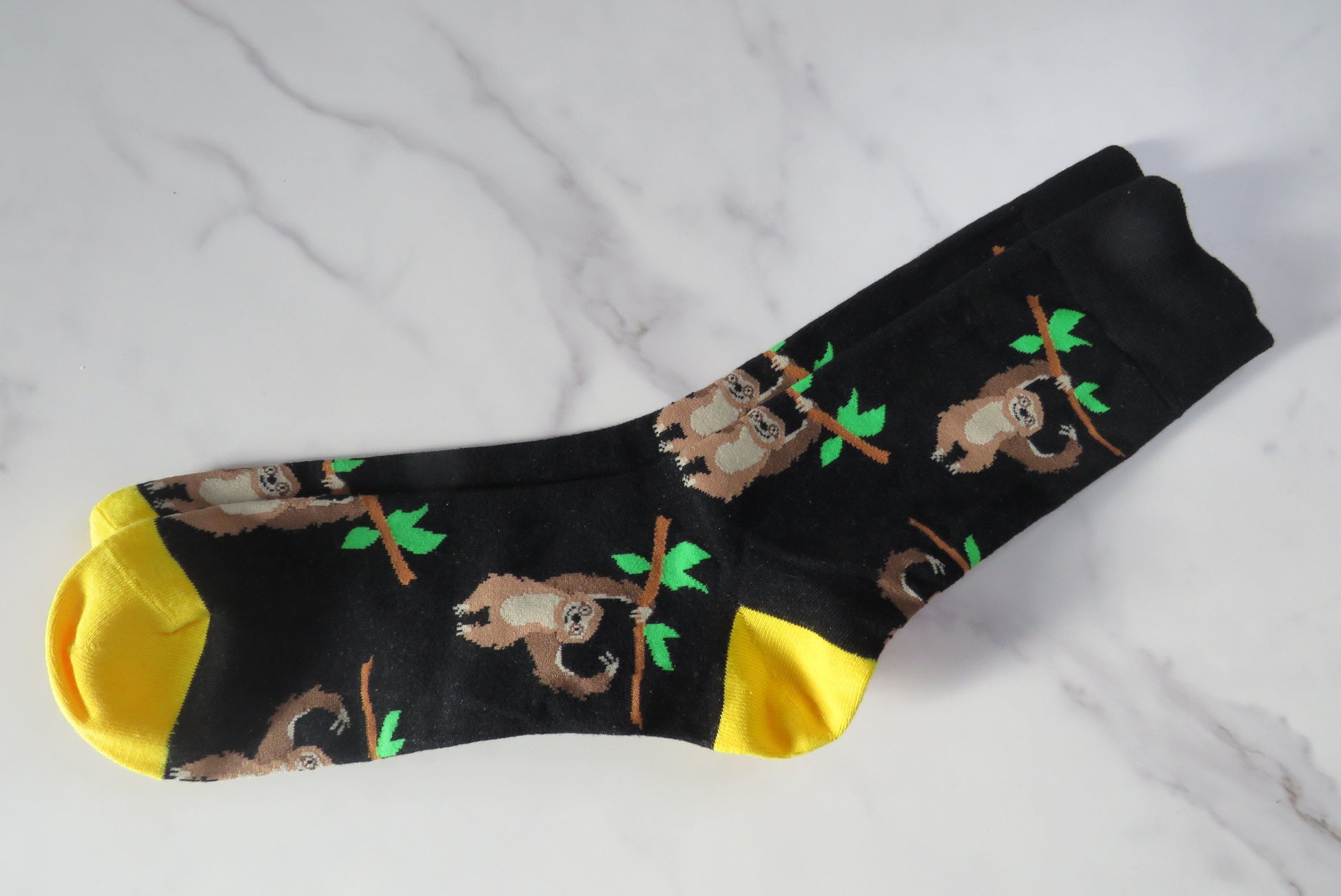 A pair of men's socks with a pattern of sloths hanging from branches.