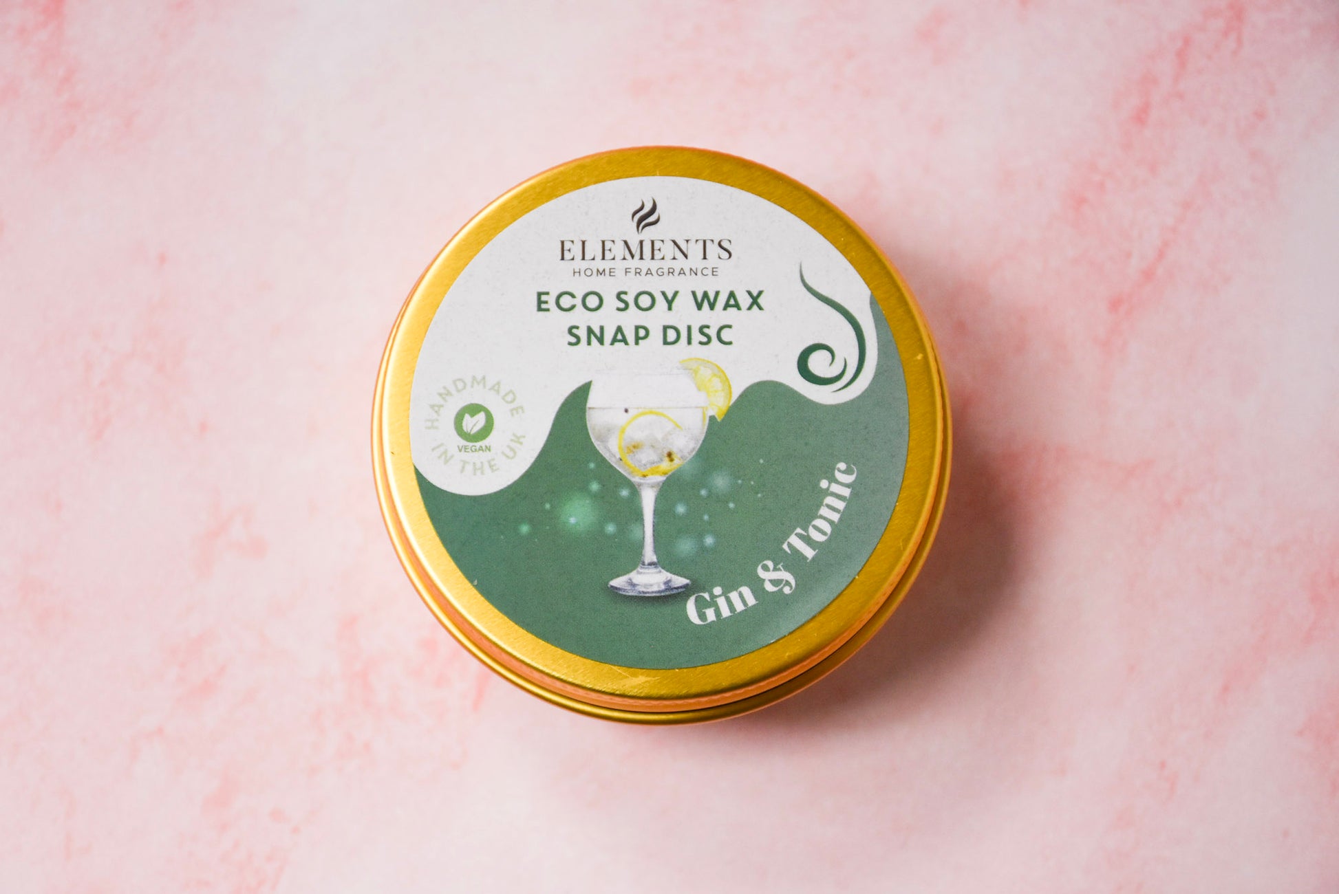 A round gold tin labelled 'Elements Home Fragrance Eco Soy Wax Snap Disc' in a Gin & Tonic scent.