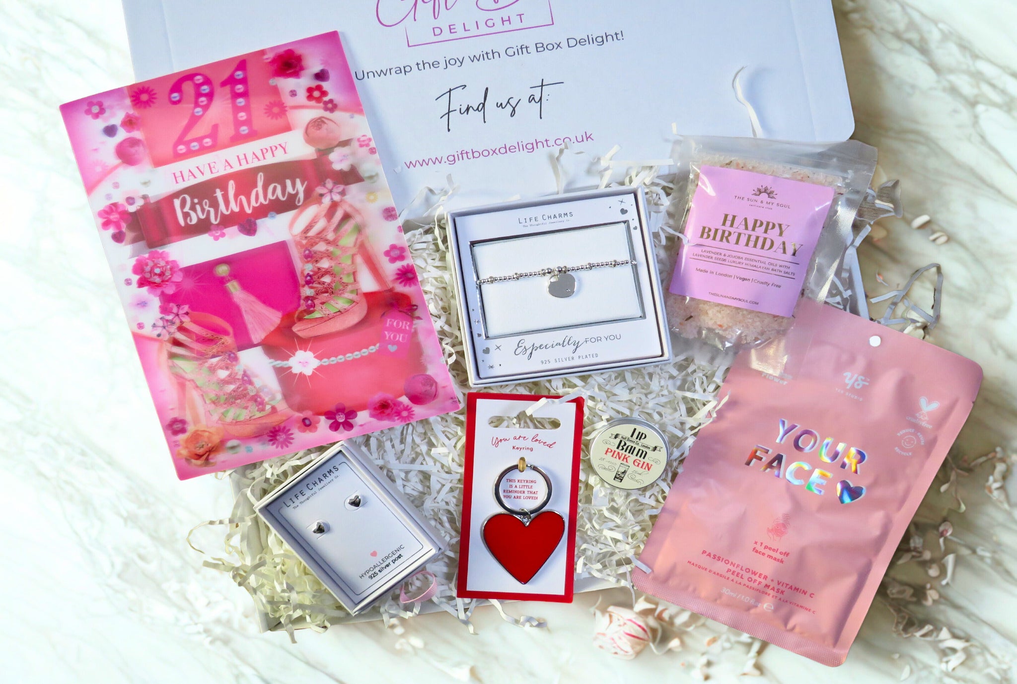 Gift box delight with various items including a card, jewelry, and skincare products.