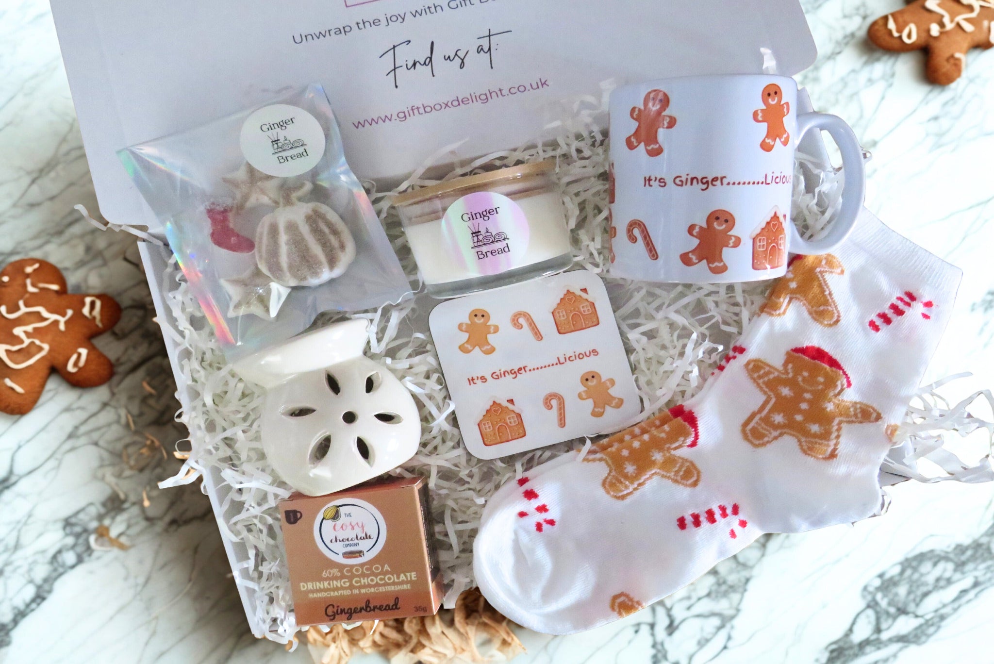 Collection of gingerbread-themed items including a mug, coaster, scented candle, cented wax melts, flower wax burner & socks.