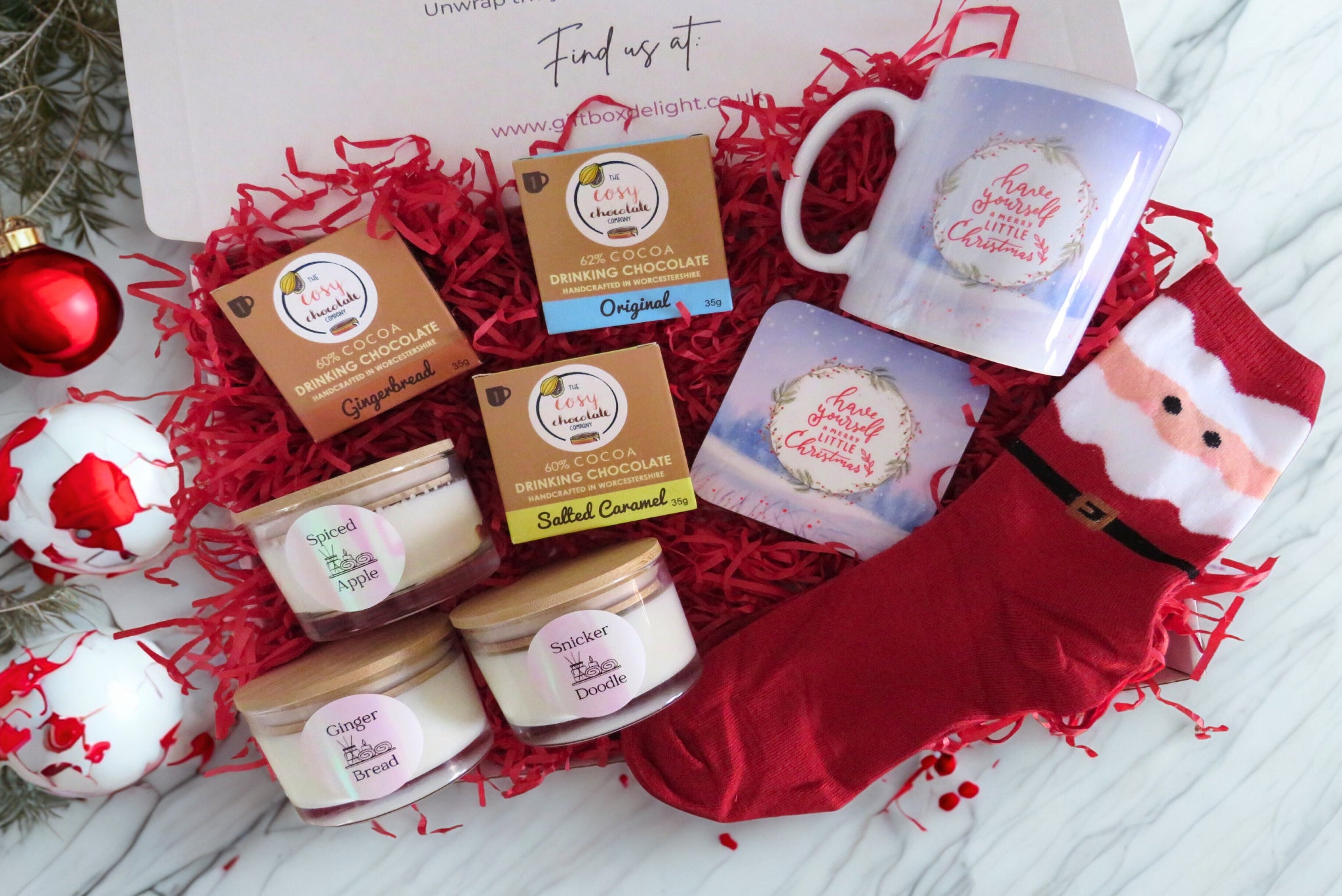 A christmas gift box with hot chocolate, scented candles, mug & coaster, santa socks.