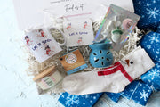 A christmas gift box with mug & coaster, hot chocolate, scented candles, scented wax melts, flower wax burner & snowman socks.
