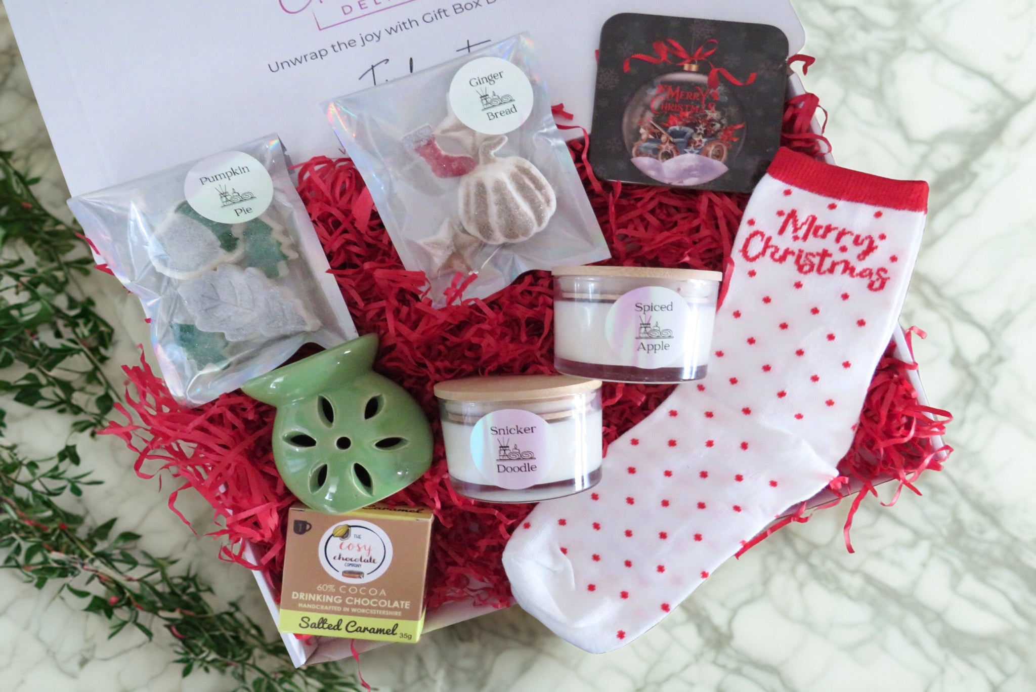 A Christmas gift box with scented wax melts, scented candles flower burner, merry christmas socks, salted caramel hot chocolate & a merry christmas coaster.