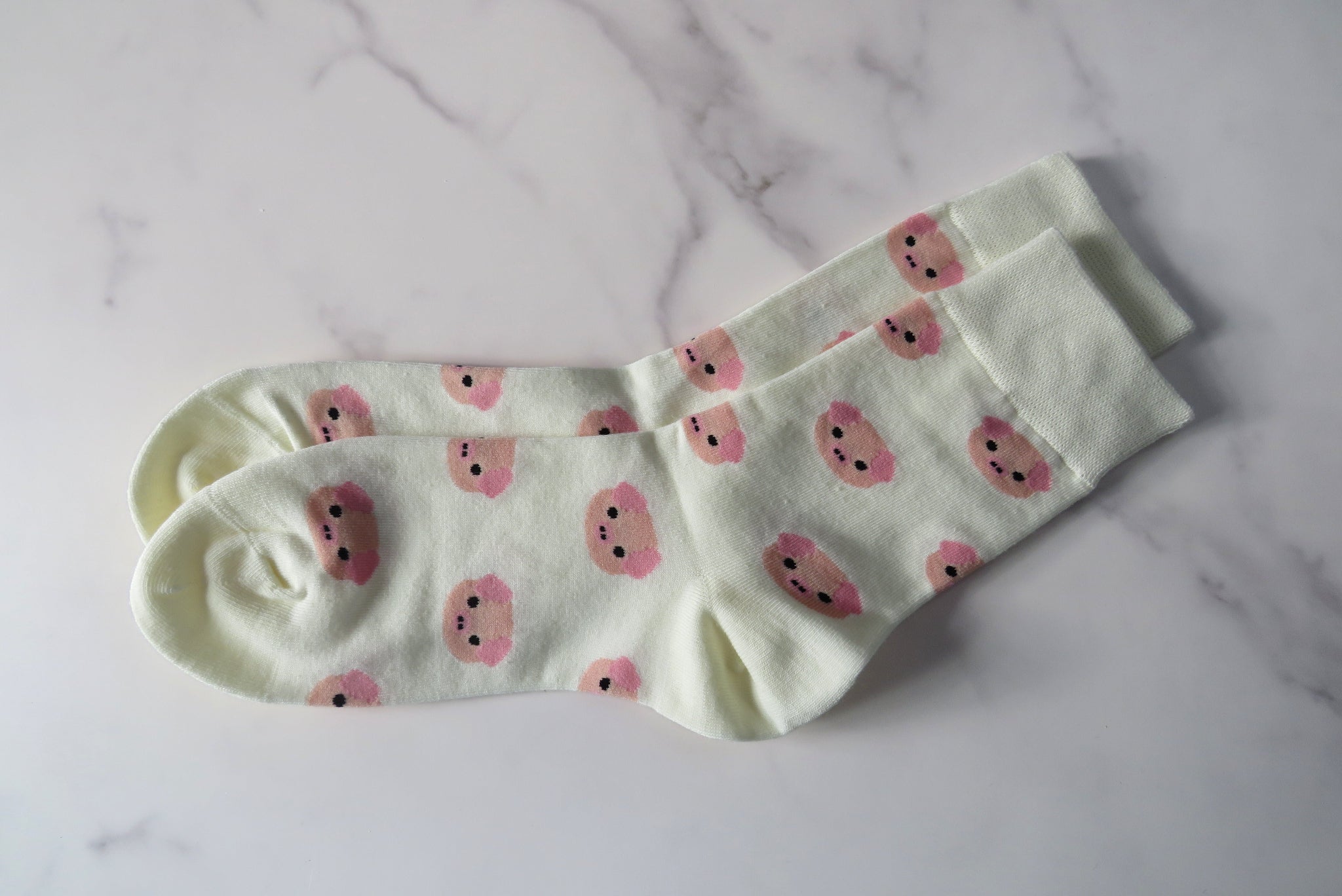 cream women's sock with pig faces on.