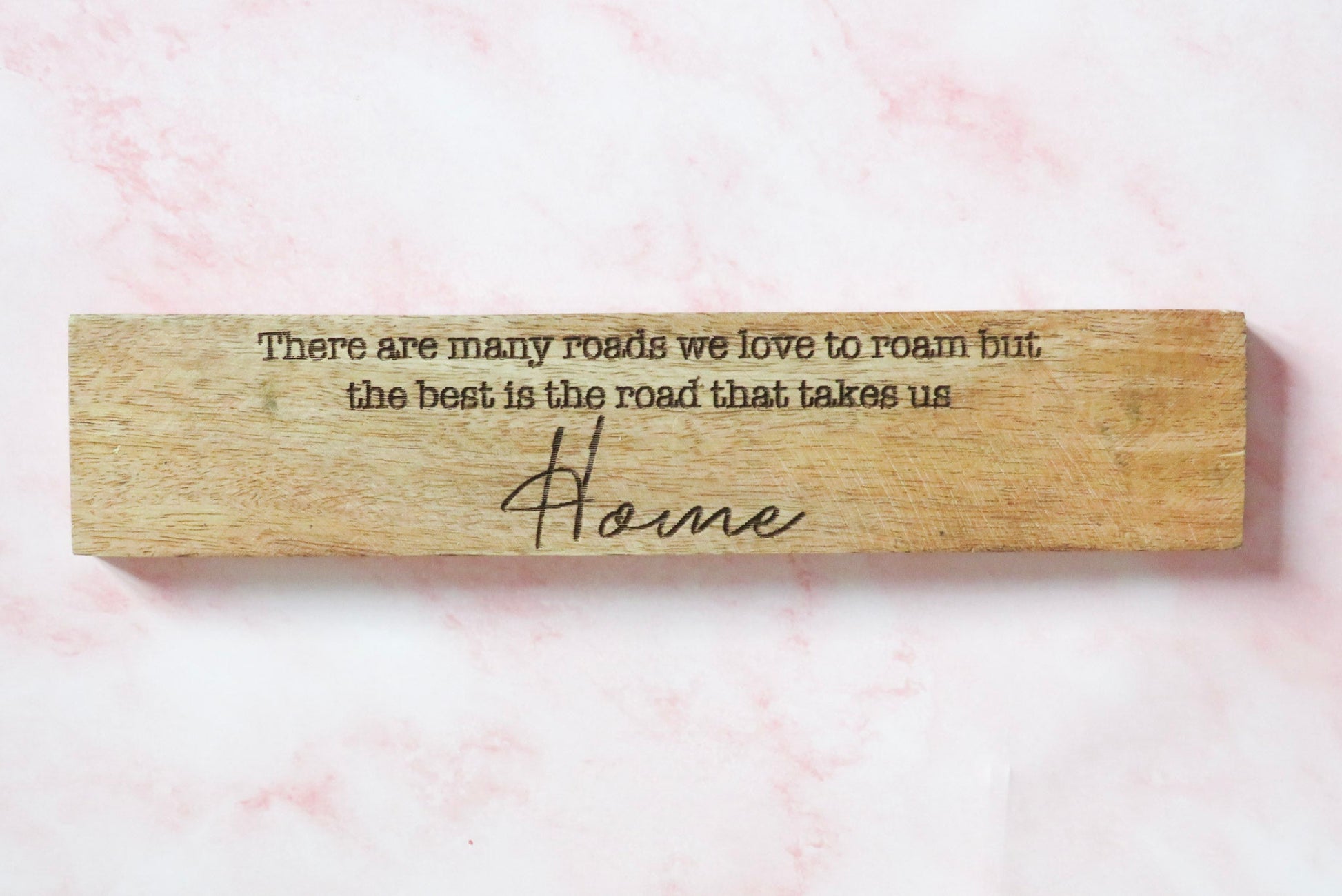 Wooden home sign with engraved text there are many roads we love to roam but the best is the road that takes us Home.